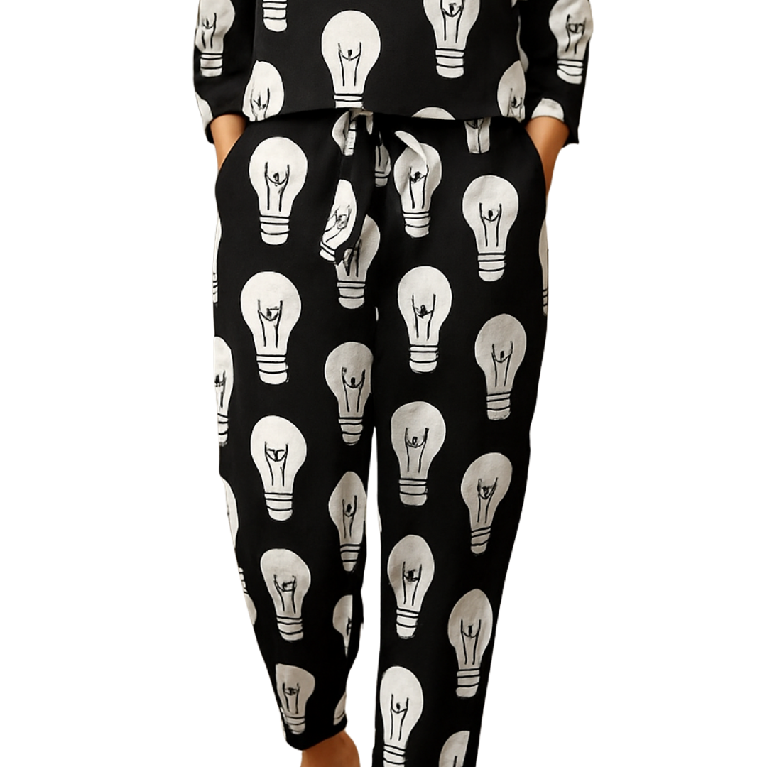 Woman wearing Lit Up Co-ord Set with black fabric covered in white hand-drawn light bulb motifs, paired with brown sandals.