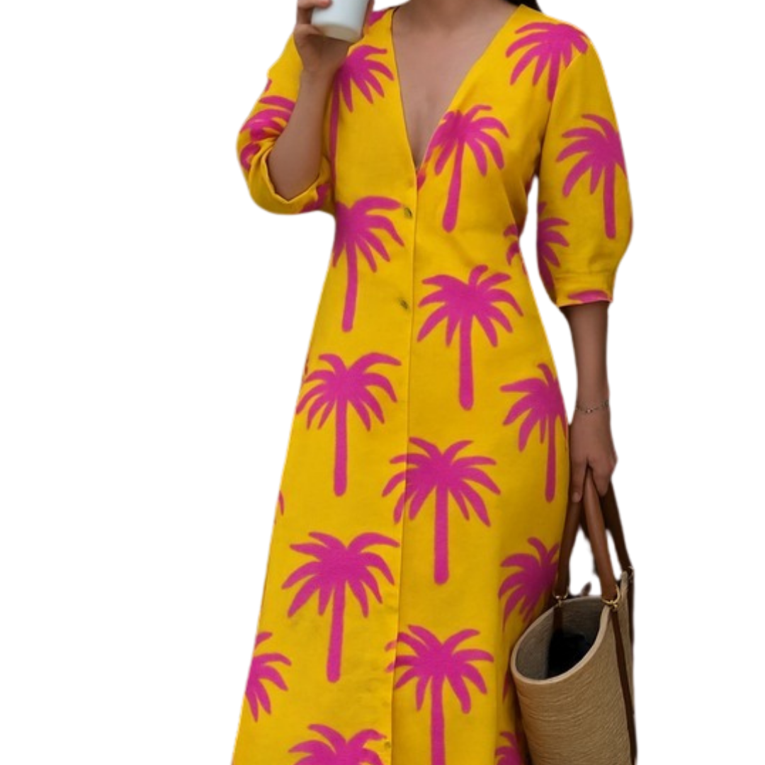 Woman wearing Tropic Like It’s Hot dress with flamingo-pink palms on sunshine-yellow, carrying a woven bag and holding a coffee cup.