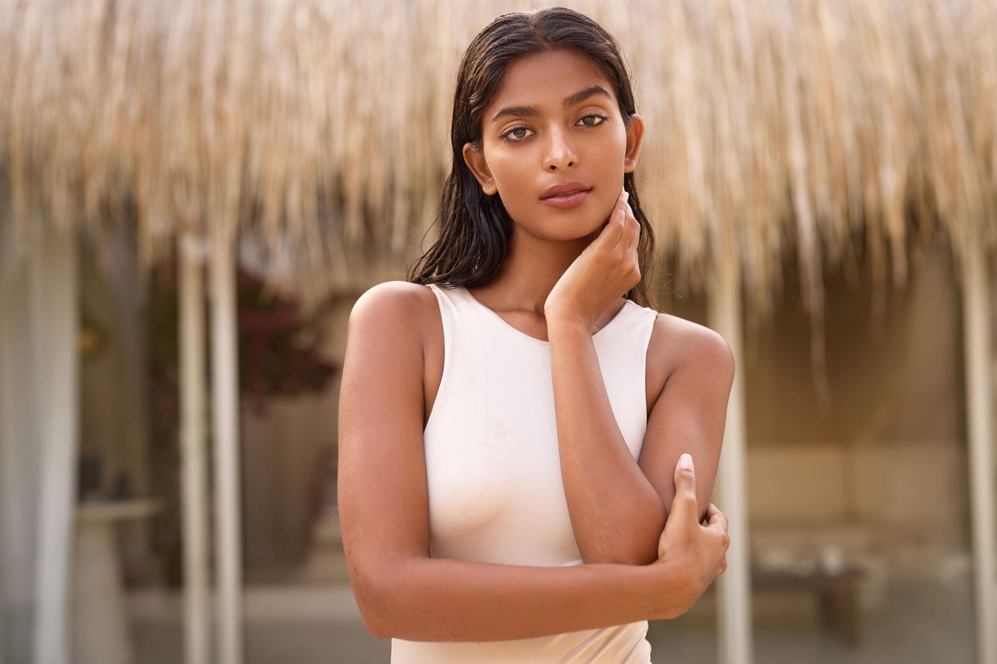Woman in a white dress standing in front of a blurred natural background