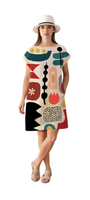 Woman wearing the Dot Dot Dash shift dress with bold geometric shapes and dopamine tones paired with a white hat and sandals