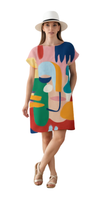 Woman wearing colorful abstract faces and bold blocks dress titled Let's Face It Dress with white hat and sandals