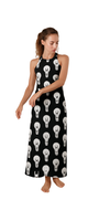 Woman wearing a black halter maxi dress with white lightbulb print, titled Maxi-Mum Voltage, standing barefoot.