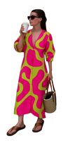 Woman wearing vibrant pink and green Neon Noir Dress holding coffee cup and straw tote bag with sunglasses.