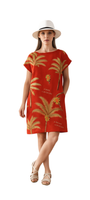 Woman wearing a burnt orange dress with hand-drawn palms titled Palm Before the Storm, paired with white hat and sandals