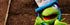 Birthday Gift Card featuring a green puppet wearing a colorful Happy Birthday hat on a wooden bench.